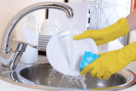 Beautiful woman with yellow dishwashing gloves washing dishes with hot water from newly installed plumbing and hot water heater Beautiful woman with yellow dishwashing gloves washing dishes with hot water from newly installed plumbing and hot water heater